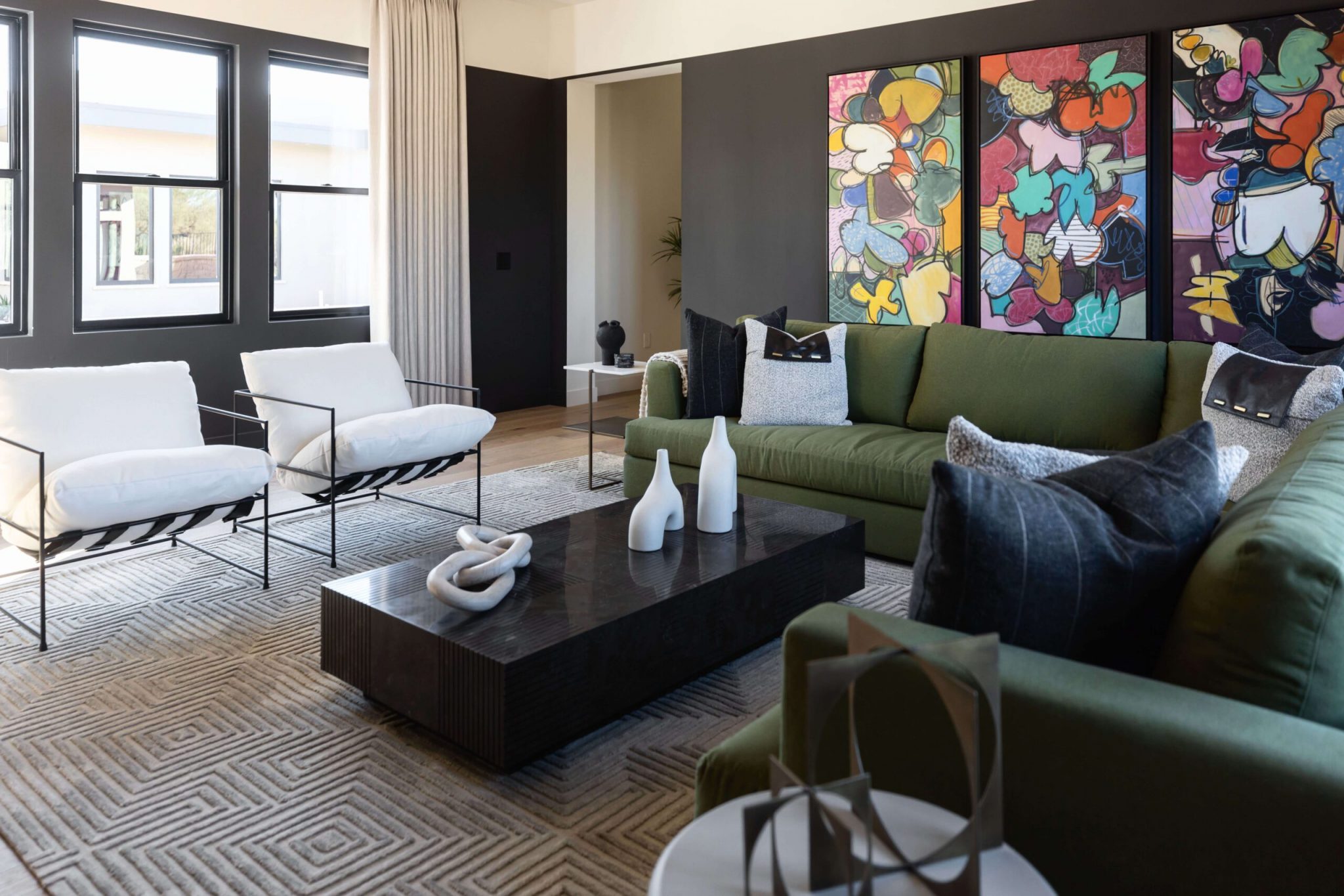 A living room with modern art and a green couch with a view of Flagstaff, AZ