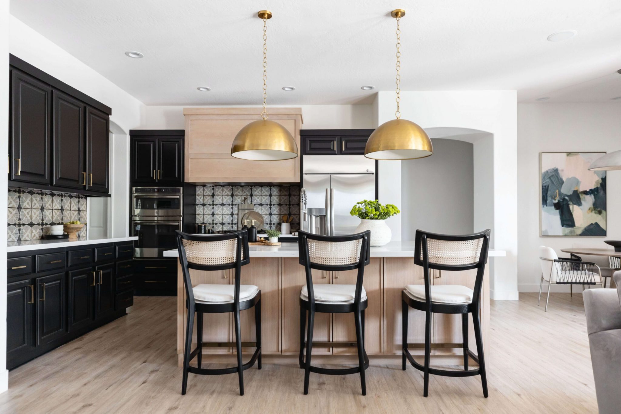 black and white chairs at a kitchen counter under gold lighting fixtures in a Flagstaff home
